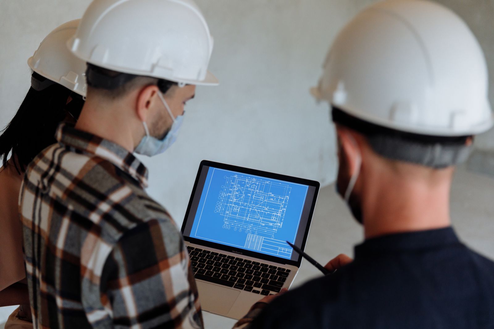 Two people in hard hats reviewing a building plan on a laptop