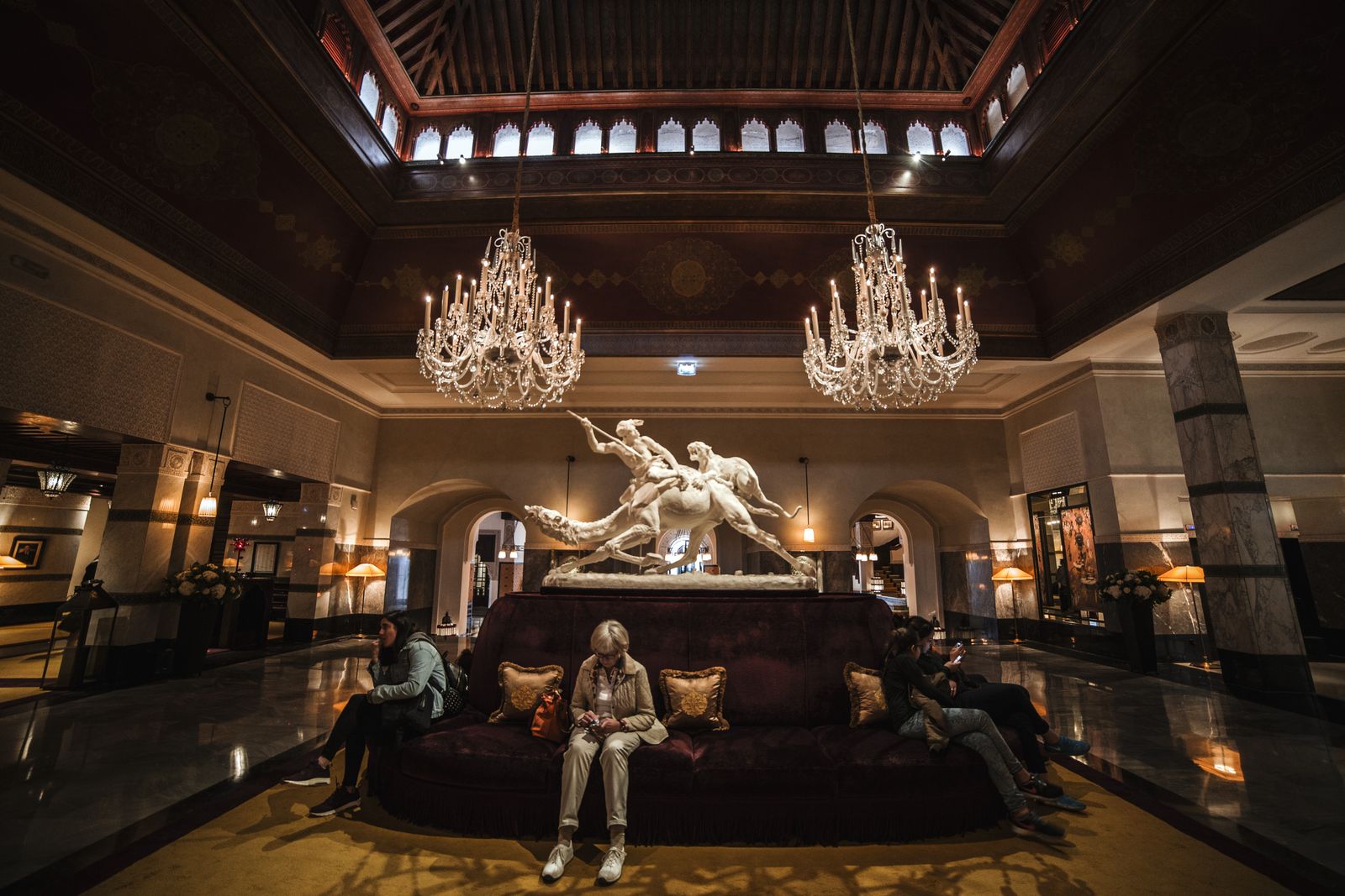 Spacious hotel lobby with chandeliers, seating groups and polished floors