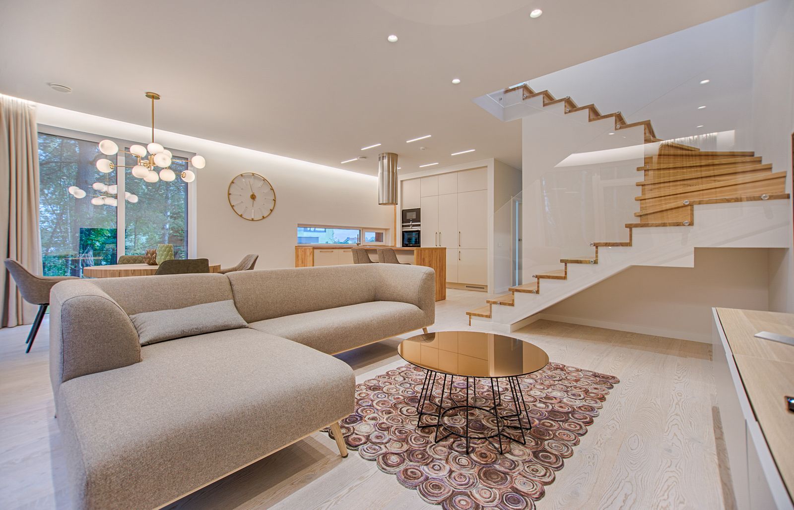Living room in neutral tones with a low sofa and a wooden staircase